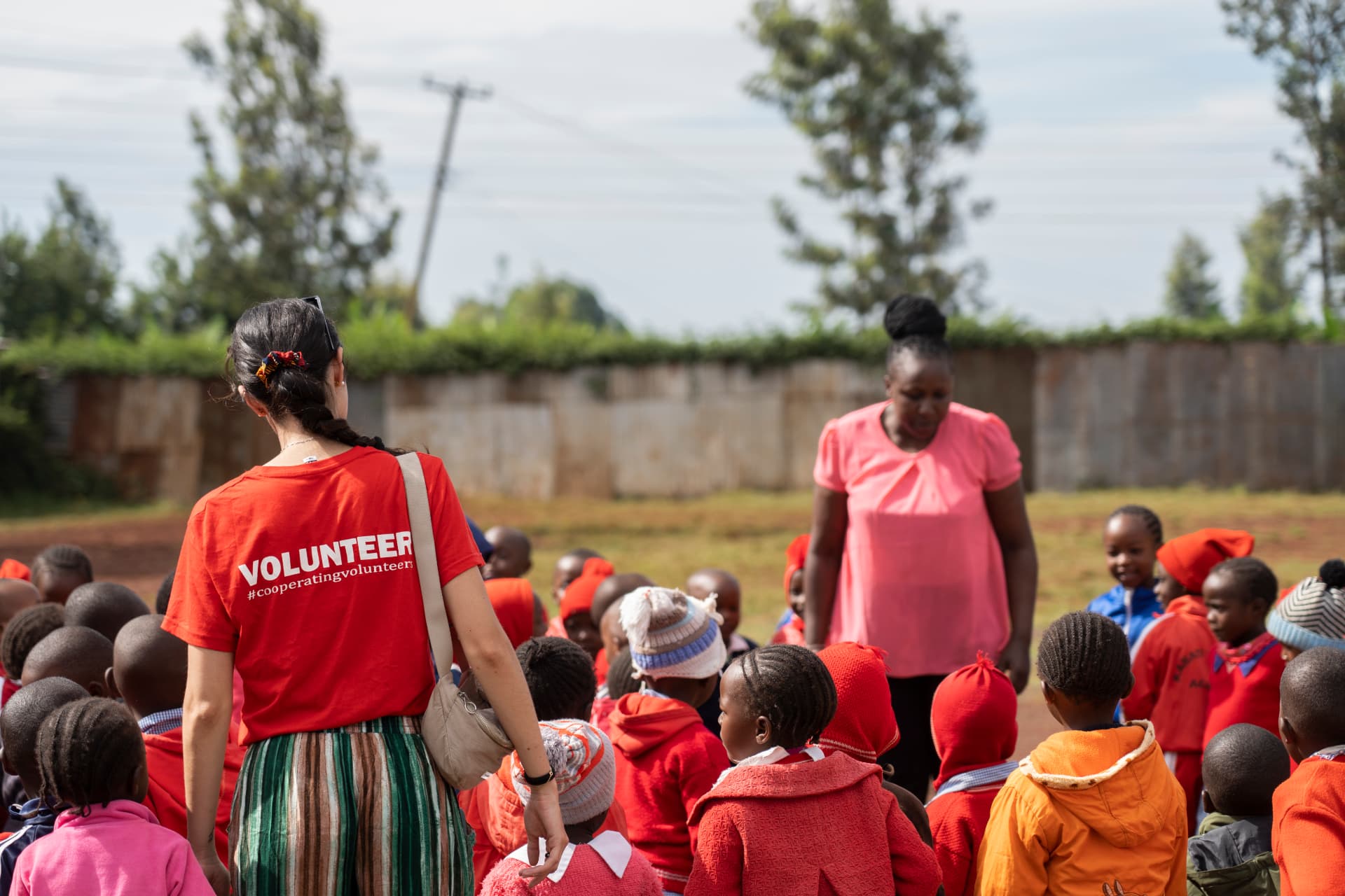 Una voluntaria de Cooperating Volunteers con niños y su cuidadora al aire libre